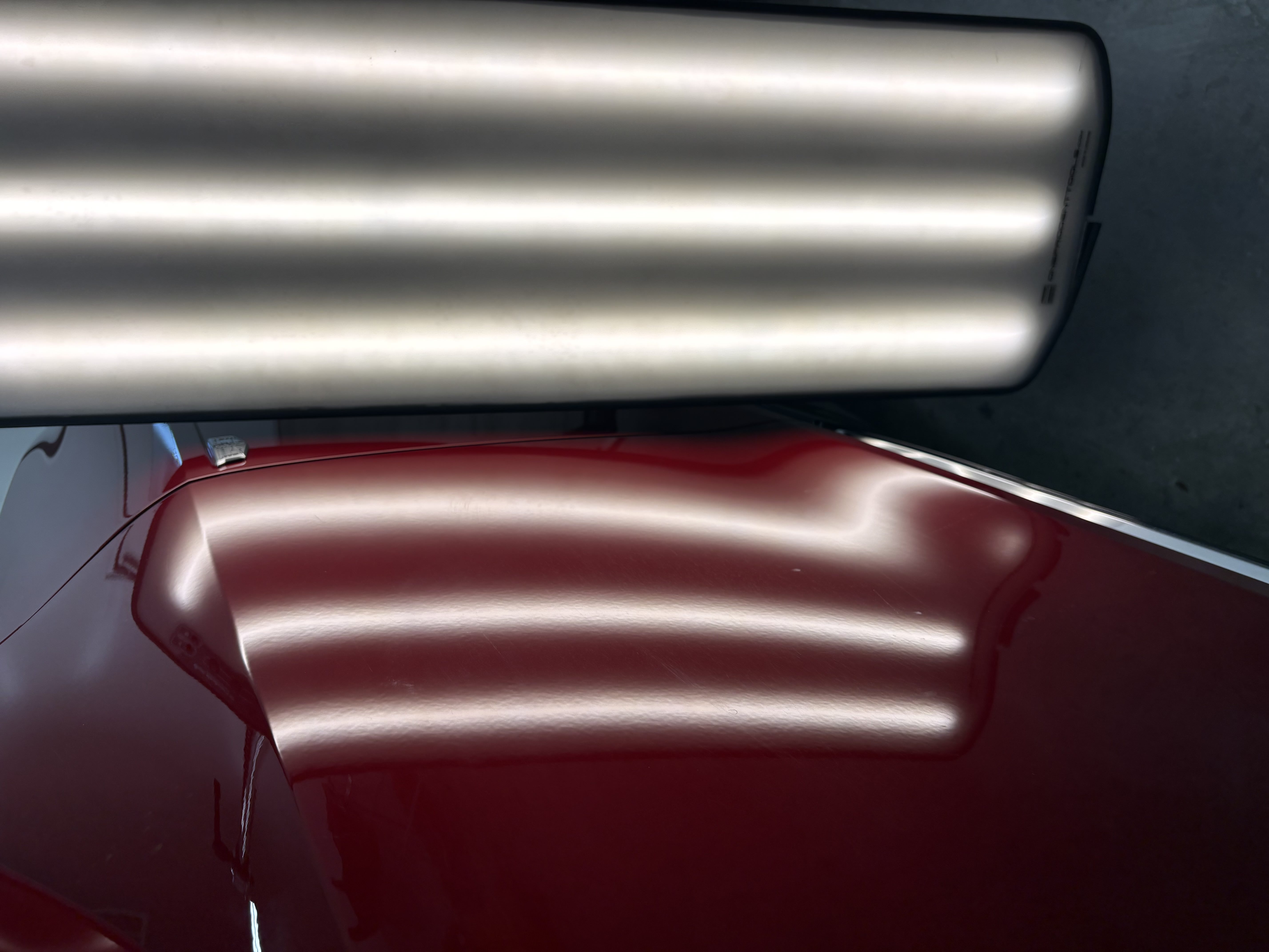 PDR line board showing a dent distorting the reflection lines on a red Cadillac